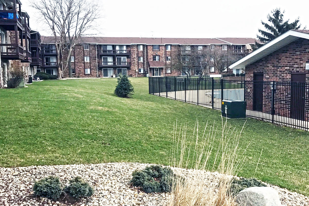 exterior of L shaped three-story brick apartment building with private balconies.